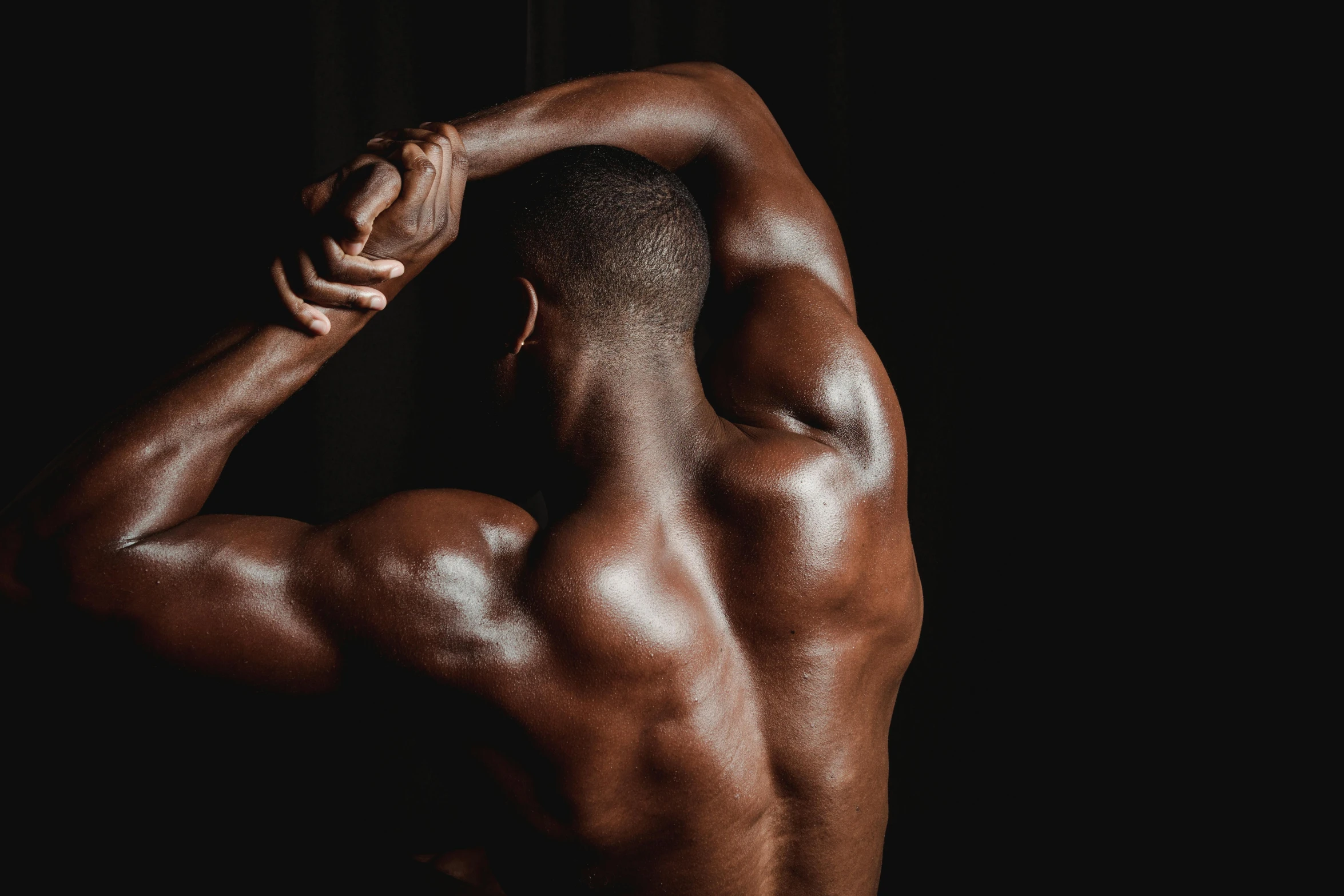 a man flexing his muscles against a black background, pexels contest winner, renaissance, black human spine, arched back, oiled skin, instagram post