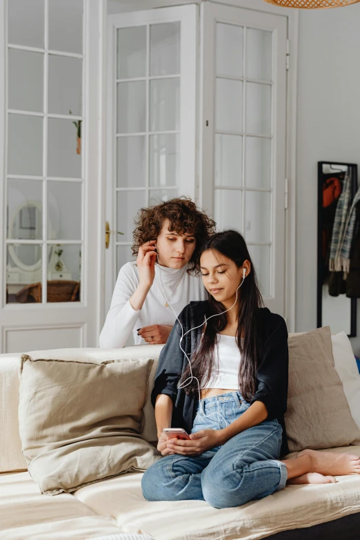 a couple of women sitting on top of a bed, trending on pexels, realism, earbuds, on a couch, teen boy, brown curly hair