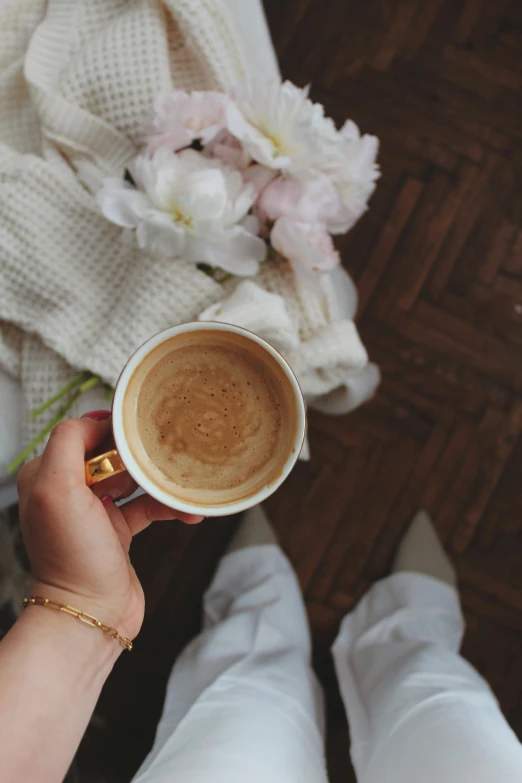 a close up of a person holding a cup of coffee, by Lucia Peka, romanticism, subtle gold accents, instagram post, flowers and gold, milk and mocha style