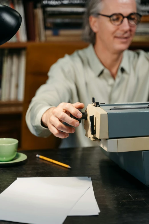 a man sitting at a table with a typewriter, unsplash, private press, slide show, teaching, low colour, action shot