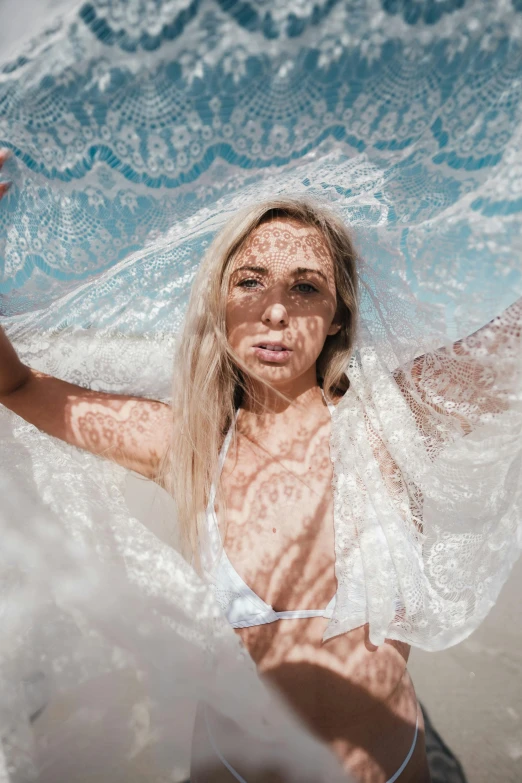 a woman in a bikini under an umbrella on the beach, inspired by Elsa Bleda, unsplash contest winner, dressed in a frilly ((lace)), close up of a blonde woman, wearing translucent sheet, photoshoot for skincare brand