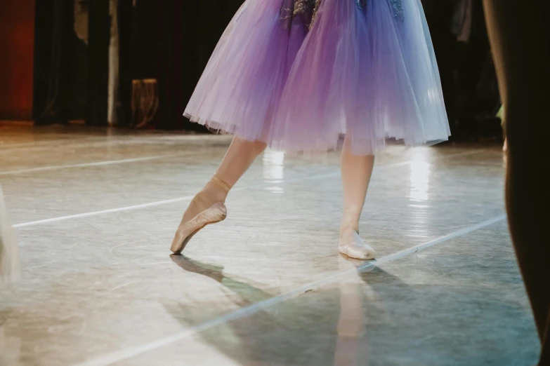 a close up of a person in a dress on a stage, by Elizabeth Polunin, pexels contest winner, arabesque, wearing purple romantic tutu, low quality footage, bare leg, schools