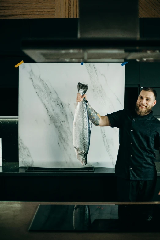 a man standing in a kitchen holding a fish, inspired by Ásgrímur Jónsson, hyperrealism, on a large marble wall, chef table, product introduction photo, rectangle