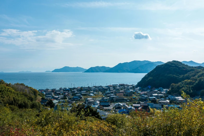 a large body of water sitting next to a lush green hillside, by Yasushi Sugiyama, unsplash, mingei, small town, views to the ocean, sakimichan, slide show