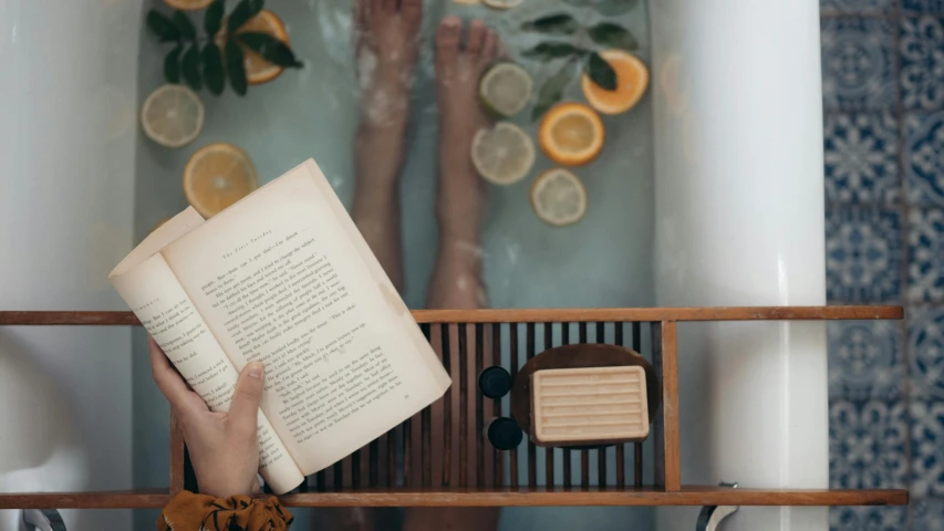 a person reading a book in a bathroom, by Emma Andijewska, pexels contest winner, on a wooden tray, skincare, sitting in the pool, 1 5 9 5
