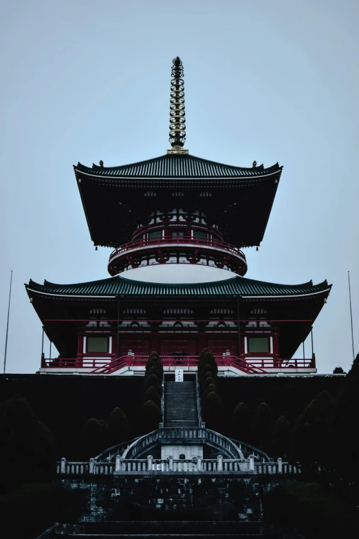 a tall building sitting on top of a lush green hillside, inspired by Itō Jakuchū, pexels contest winner, crimson themed, lead - covered spire, front face, front view