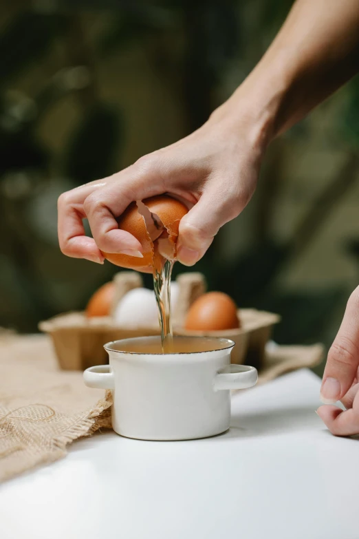 a person squeezing an egg into a cup, a still life, unsplash, made of glazed, brown, gardening, caramel