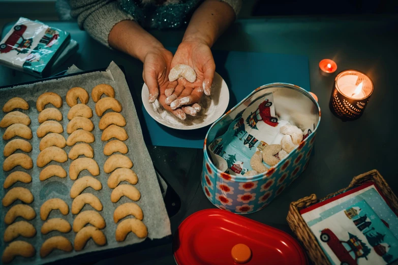 a person holding a plate of cookies next to a tray of cookies, a still life, by Julia Pishtar, pexels contest winner, frying nails, community celebration, at night, dumplings on a plate