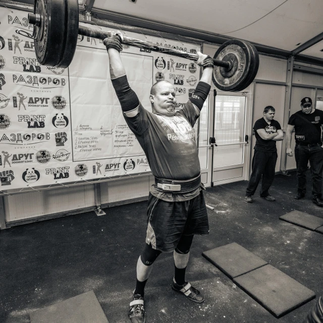 a man lifting a barbell in a gym, a black and white photo, by Adam Marczyński, pexels contest winner, standing triumphant and proud, tournament, tjalf sparnaay 8 k, emily rajtkowski