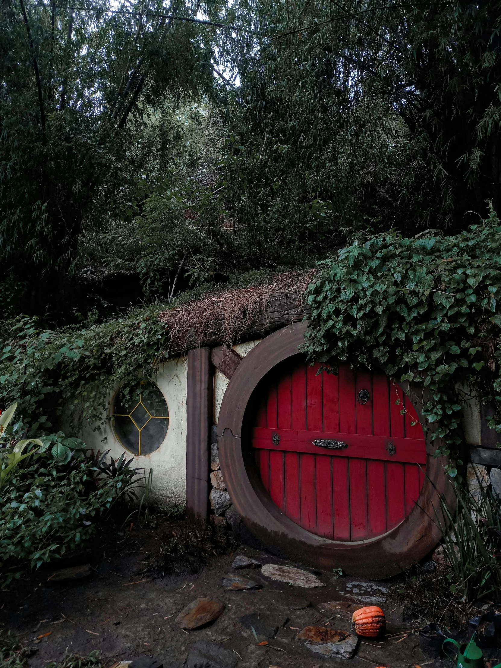 a red door sitting in the middle of a forest, style of lord of the rings, garden, slight overcast lighting, taken in 2022