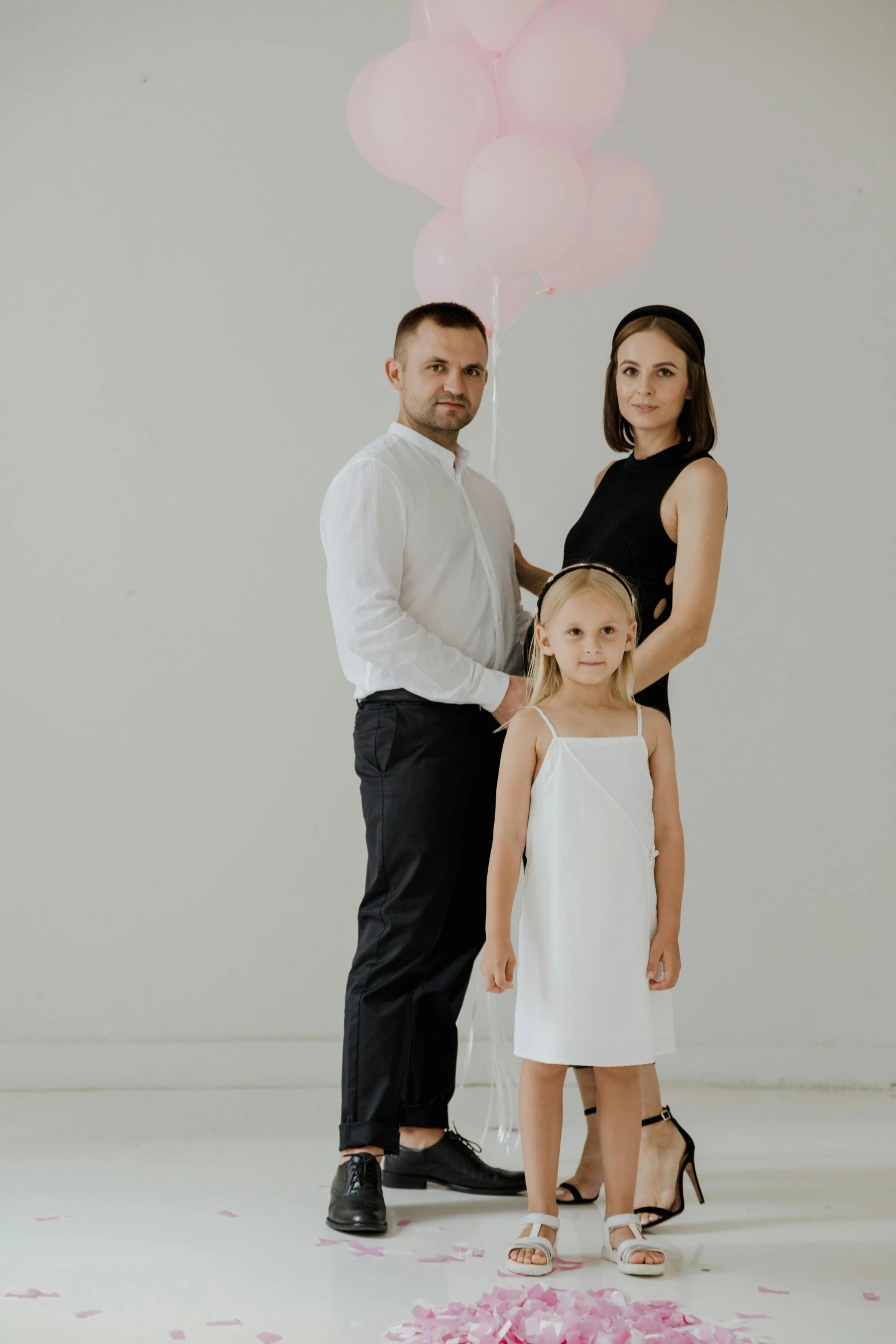 a man and woman standing next to a little girl, a portrait, pexels contest winner, conceptual art, white backdrop, balloon, promotional image, elegantly