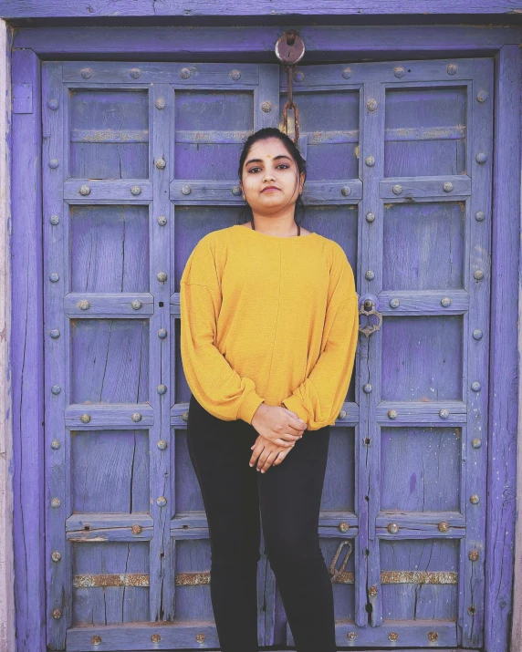 a woman standing in front of a blue door, an album cover, pexels contest winner, young himalayan woman, yellow purple, posing!!, ((portrait))