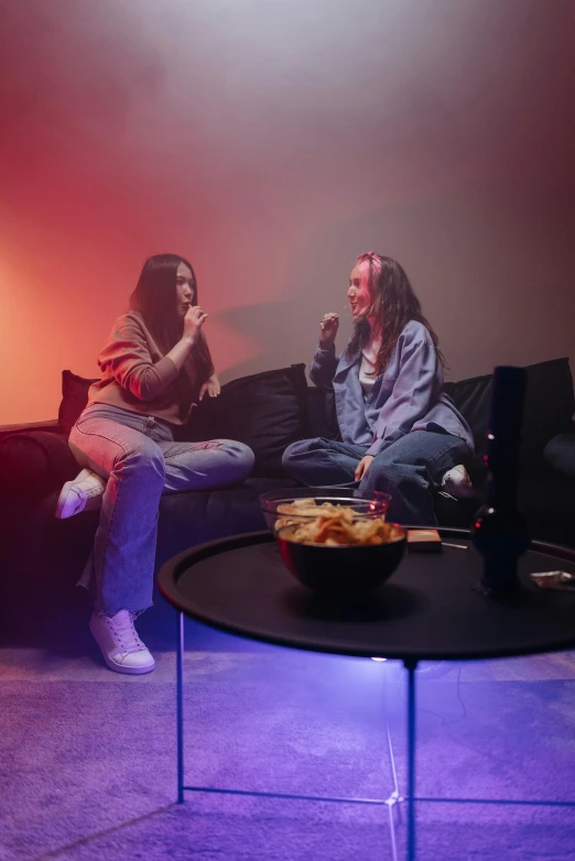 a couple of people sitting on top of a couch, antipodeans, smoking a bowl of hash together, with neon lights, her friend, high quality photo
