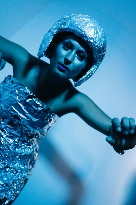 a woman in a silver dress holding a tennis racquet, inspired by Cindy Sherman, unsplash, holography, wearing a space helmet, blue body, dancer, spaceman standing looking