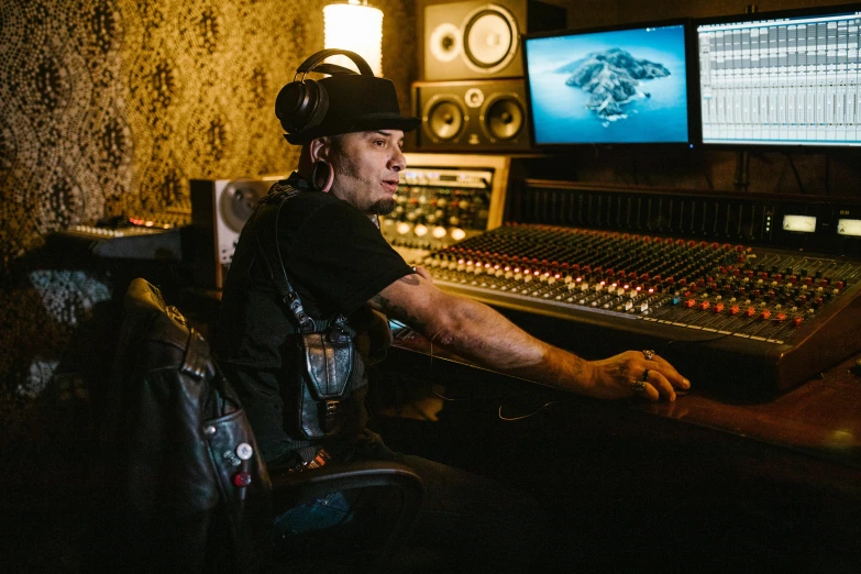 a man sitting in front of a mixing desk, an album cover, pexels, process art, tattooed, sitting at a control center, billy christian, studio lit