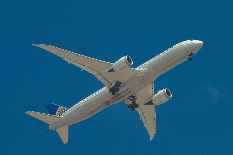 a large jetliner flying through a blue sky, by Carey Morris, pexels contest winner, arabesque, gold, plain background, slide show, 5 feet away