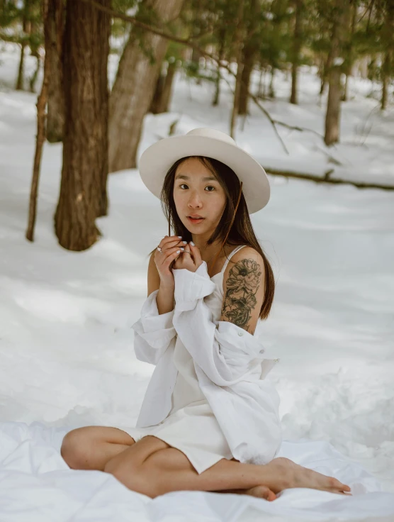 a woman sitting in the snow with a hat on, inspired by Itō Shinsui, pexels contest winner, white long tanktop, forest picnic, of taiwanese girl with tattoos, nico wearing a white dress