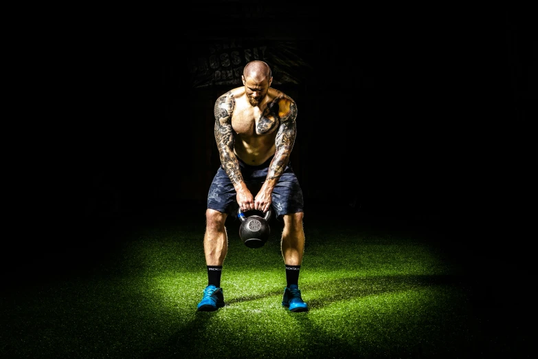 a man holding a kettlebell in the dark, a photo, by Adam Marczyński, pexels contest winner, full body 8k, lawns, tattooed, profile image