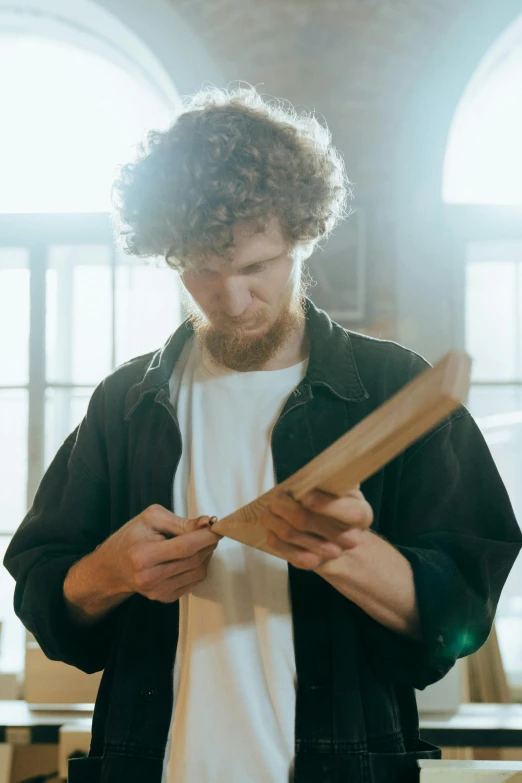 a man holding a piece of wood in his hands, pexels contest winner, renaissance, with a curly perm, inspect in inventory image, focused light, high quality paper