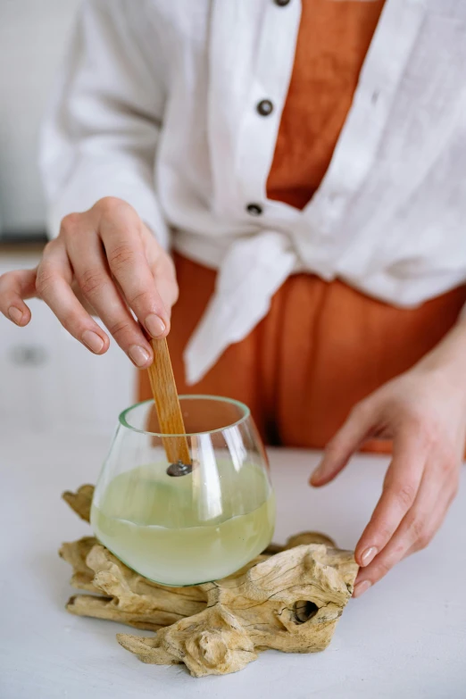 a woman stirring up a drink with a wooden spoon, inspired by Li Di, trending on pexels, renaissance, zen aesthetic, made of glazed, green tea, ginger