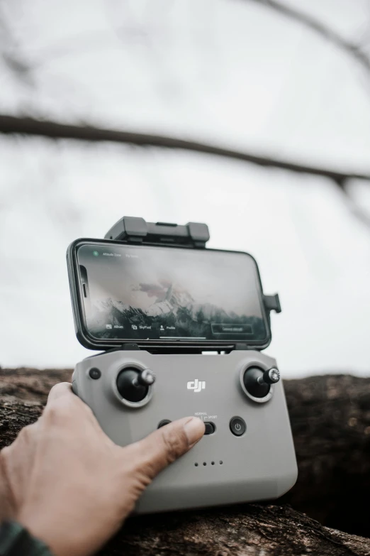 a person holding a game controller in their hand, trending on pexels, trail cam footage, drones in the sky, looking at his phone, grey