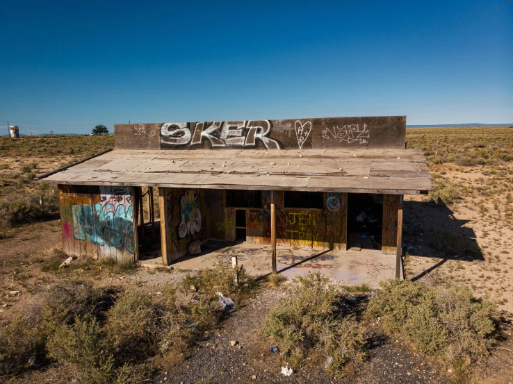 a building with graffiti on it in the middle of the desert, by Bertram Brooker, graffiti, old shops, old cabin, sunken, 8 k -