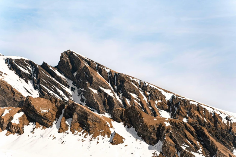 a man riding a snowboard down the side of a snow covered mountain, an album cover, pexels contest winner, geological strata, reykjavik, seen from a distance, brown