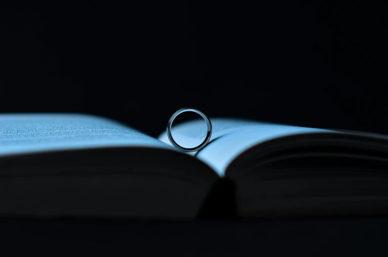 a ring sitting on top of an open book, by Niko Henrichon, pexels contest winner, romanticism, vantablack chiaroscuro, minimal canon 5 0 mm, 15081959 21121991 01012000 4k, hook as ring