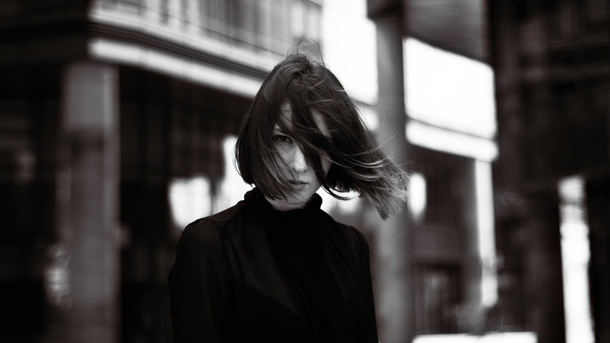 a black and white photo of a woman walking down the street, pexels contest winner, bauhaus, black bob cut hair, wind blowing hair, ((portrait)), kirsi salonen