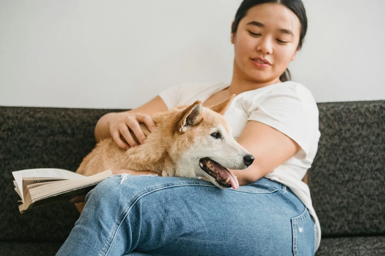 a woman sitting on a couch holding a dog, trending on pexels, visual art, a young asian woman, manuka, 1450, thumbnail