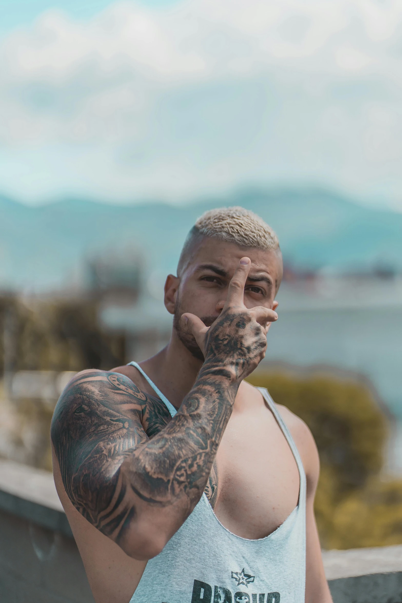 a man in a tank top smoking a cigarette, a tattoo, inspired by Elsa Bleda, pexels contest winner, with mountains in the background, ronaldo nazario, twitch streamer / gamer ludwig, non binary model