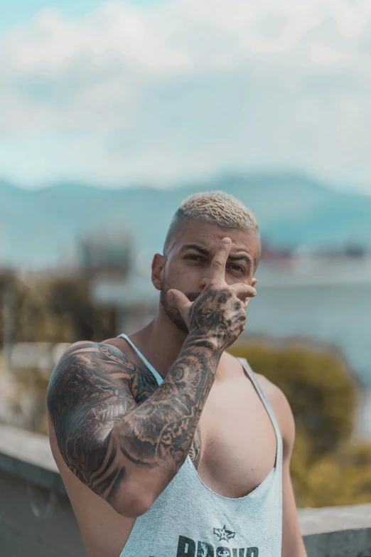 a man in a tank top smoking a cigarette, a tattoo, inspired by Elsa Bleda, pexels contest winner, with mountains in the background, ronaldo nazario, twitch streamer / gamer ludwig, non binary model