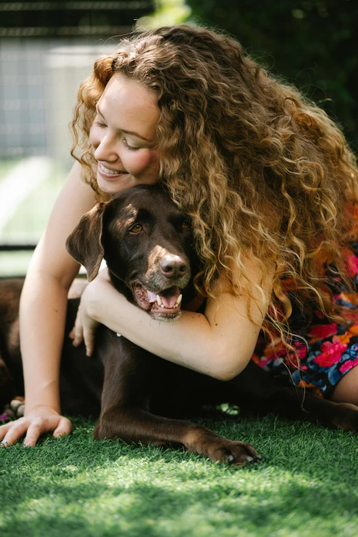 a woman laying on the grass with two dogs, a portrait, by Matt Cavotta, pexels contest winner, brown curly hair, profile image, holding paws, australian