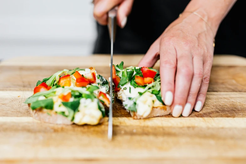 a close up of a person cutting food on a cutting board, by Julia Pishtar, profile image, fan favorite, cooking pizza, eating garlic bread