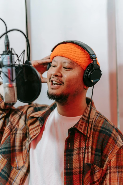 a man wearing headphones in front of a microphone, an album cover, inspired by Pablo Carpio, trending on pexels, asian male, singing, studio orange, indonesia