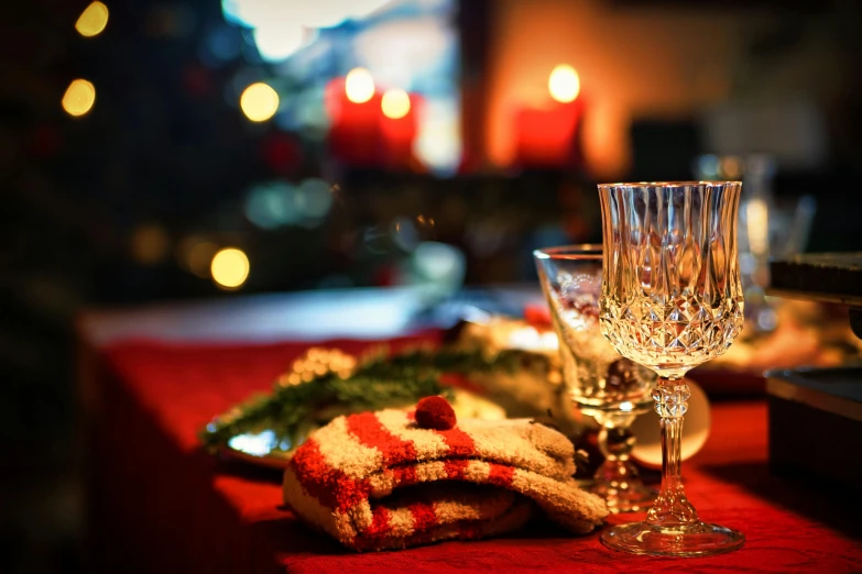 a table topped with a plate of food next to a wine glass, by Julia Pishtar, shutterstock, christmas night, red and gold cloth, slightly pixelated, cosy atmoshpere