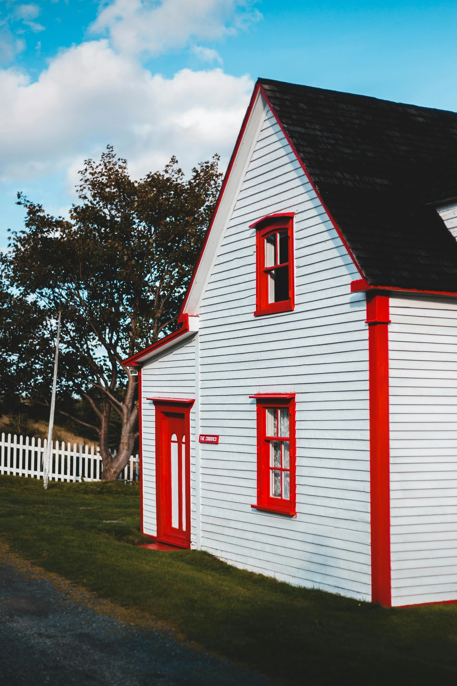 a white house with red trim and a black roof, pexels contest winner, countryside, vivid colour, light house, exterior