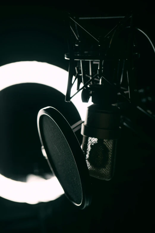 a microphone and a light in a dark room, an album cover, pexels contest winner, light and space, huge black circle, radio equipment, in a studio hollow, news broadcast