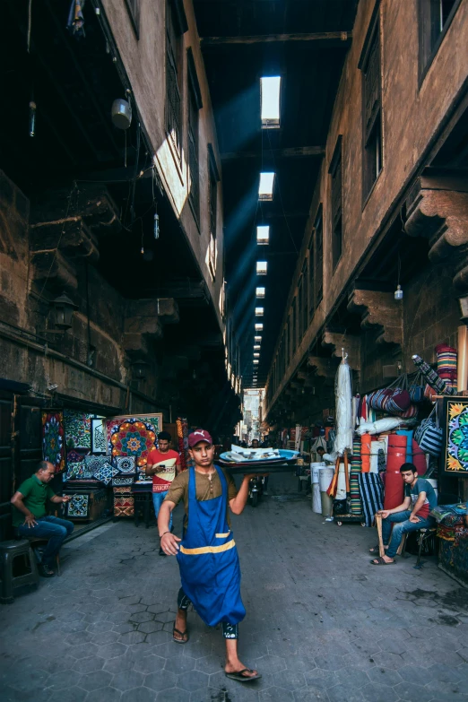 a man in a blue dress walking down a street, by Youssef Howayek, pexels contest winner, graffiti, inside an arabian market bazaar, rapper, egyptian clothes, wide view