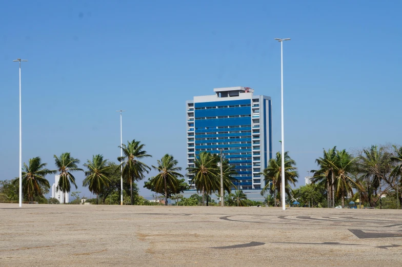 an empty parking lot with a tall building in the background, hurufiyya, in a beachfront environment, dakar, square, lê long