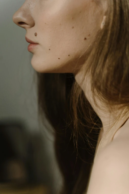 a close up of a woman with long hair, a tattoo, inspired by Elsa Bleda, trending on pexels, sparse freckles, collar around neck, drawn with dots, long chin