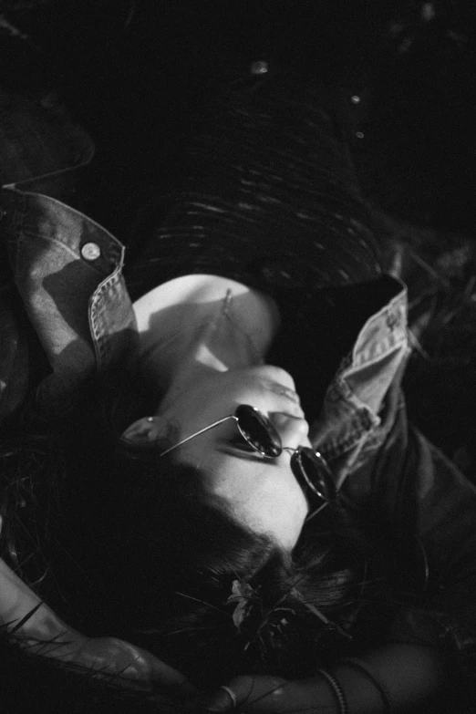 a black and white photo of a woman laying on the ground, inspired by Max Dupain, tumblr, in an old 1950s leather jacket, **cinematic, with sunglass, nighttime