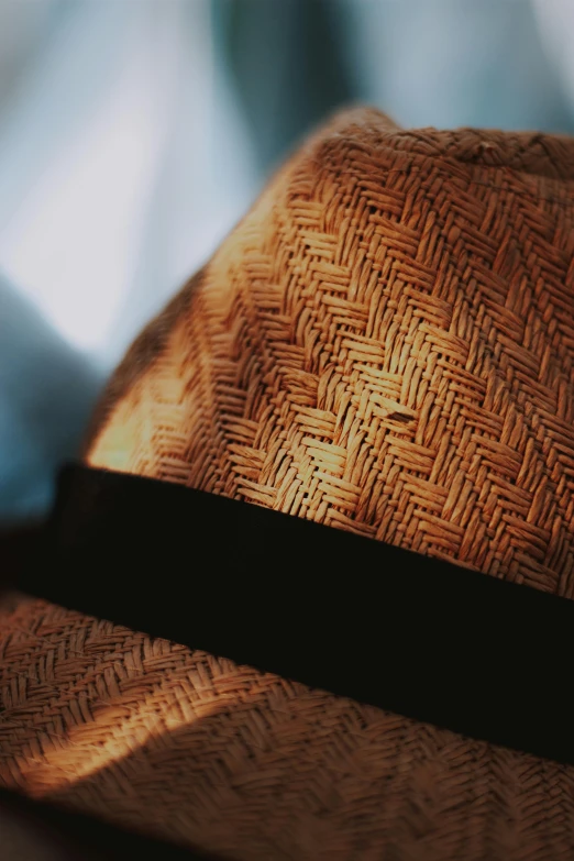 a hat sitting on top of a wooden table, up-close, weave, brown atmospheric lighting, zoomed in