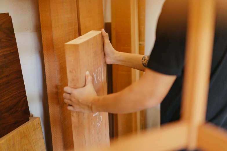 a close up of a person holding a piece of wood, contaning tables and walls, profile image