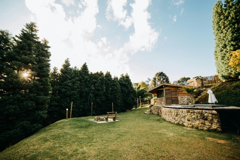 a hot tub sitting on top of a lush green field, unsplash, rustic stone cabin in horizon, bulli, lawns, in avila pinewood