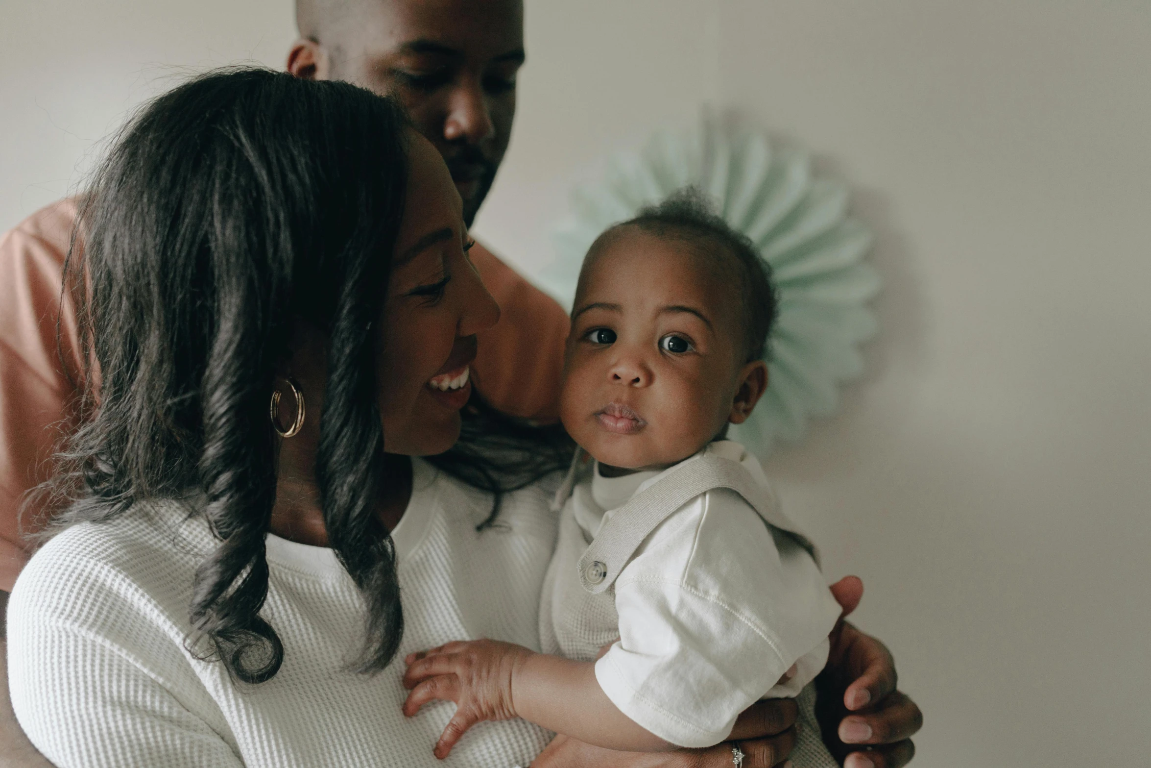 a man standing next to a woman holding a baby, pexels contest winner, dark skin tone, 1 5 0 4, toddler, 1 2 9 7