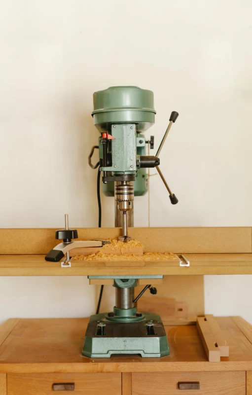 a drill press sitting on top of a wooden table, by Matthias Stom, brian ingram, multi - level, sand, small manufacture