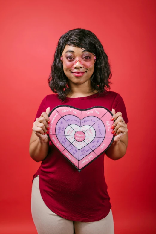 a woman holding a paper heart on a red background, pexels contest winner, nerdy black girl super hero, dart board, red and purple coloring, female calendar