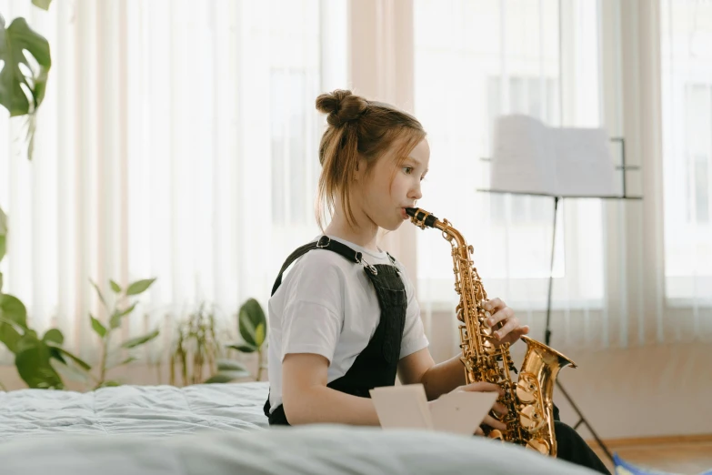 a little girl sitting on a bed playing a saxophone, pexels contest winner, greta thunberg, girl wearing uniform, long neck, sydney hanson