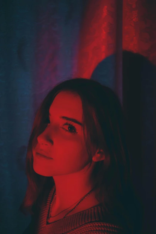 a woman standing in front of a red light, an album cover, inspired by Elsa Bleda, portrait of emma watson, low saturated red and blue light, asher duran, grainy filter